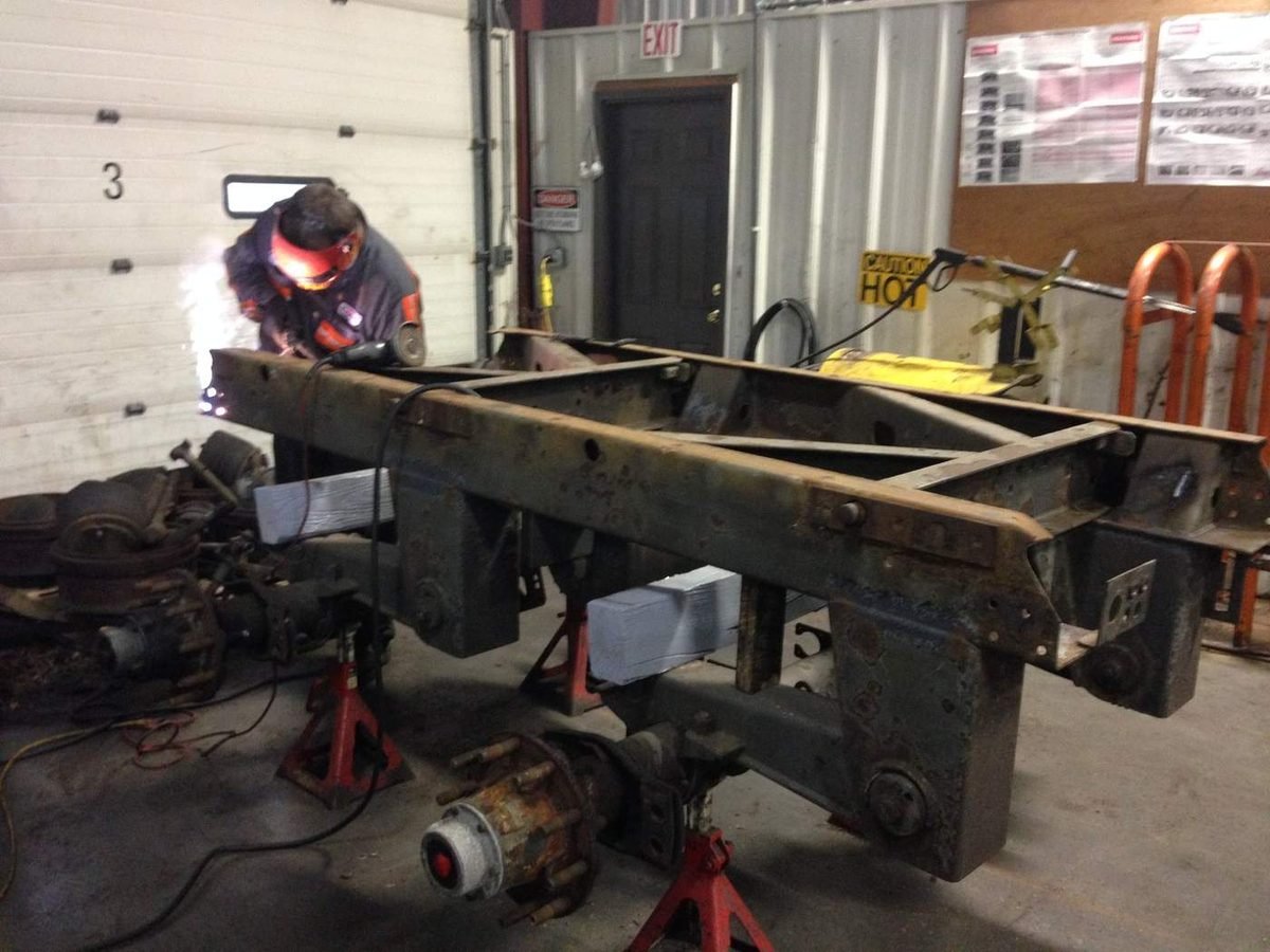 Heavy truck frame and rear suspension on jack stands during a welding rebuild
